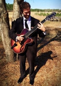 Taylor Roberts with guitar under tree March 2014