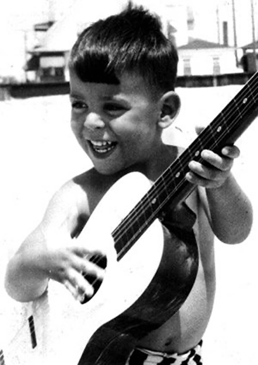Howard Paul as a child holding a guitar
