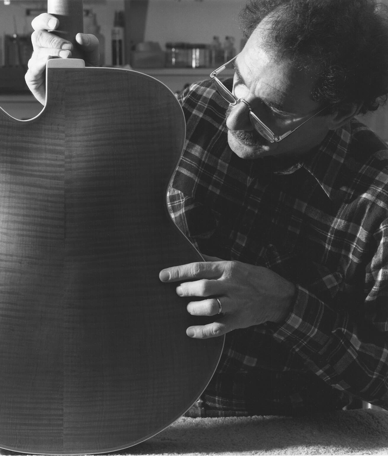 Robert Benedetto examining back of a guitar black and white