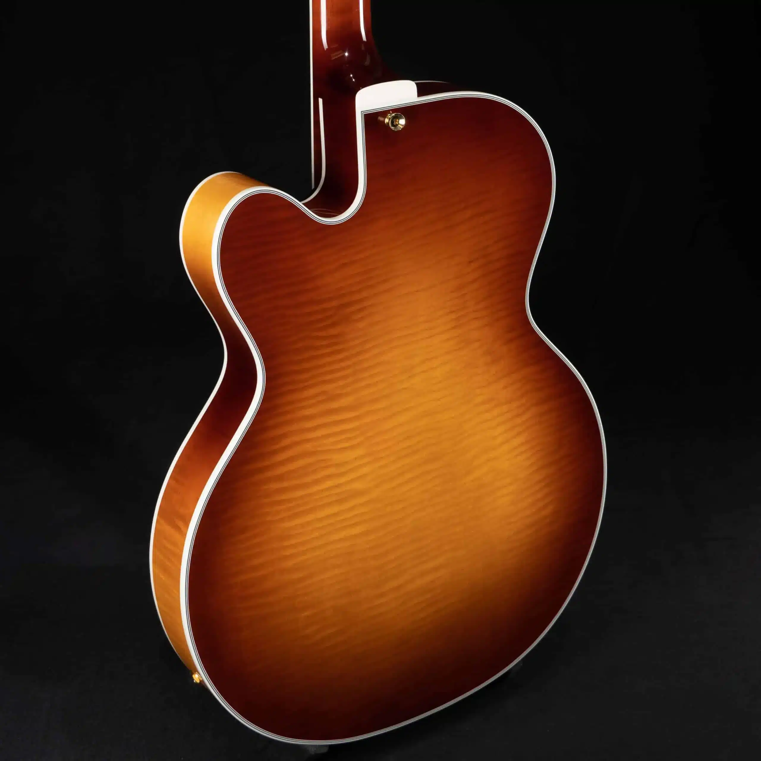 Full view of the flamed maple back and neck of a sunburst archtop guitar against a black background.