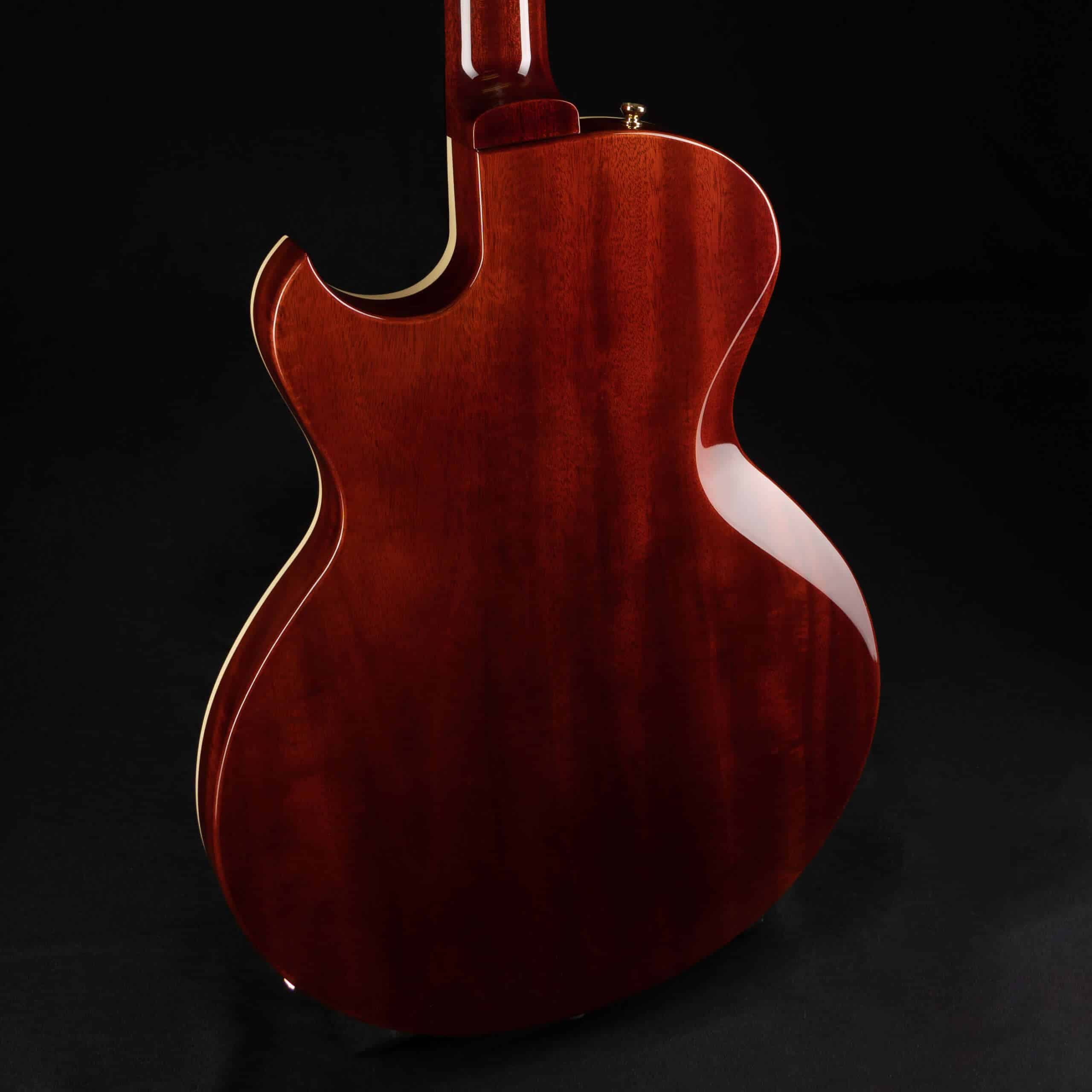 The mahogany back and neck heel of a single-cutaway guitar with cream binding over a black background.