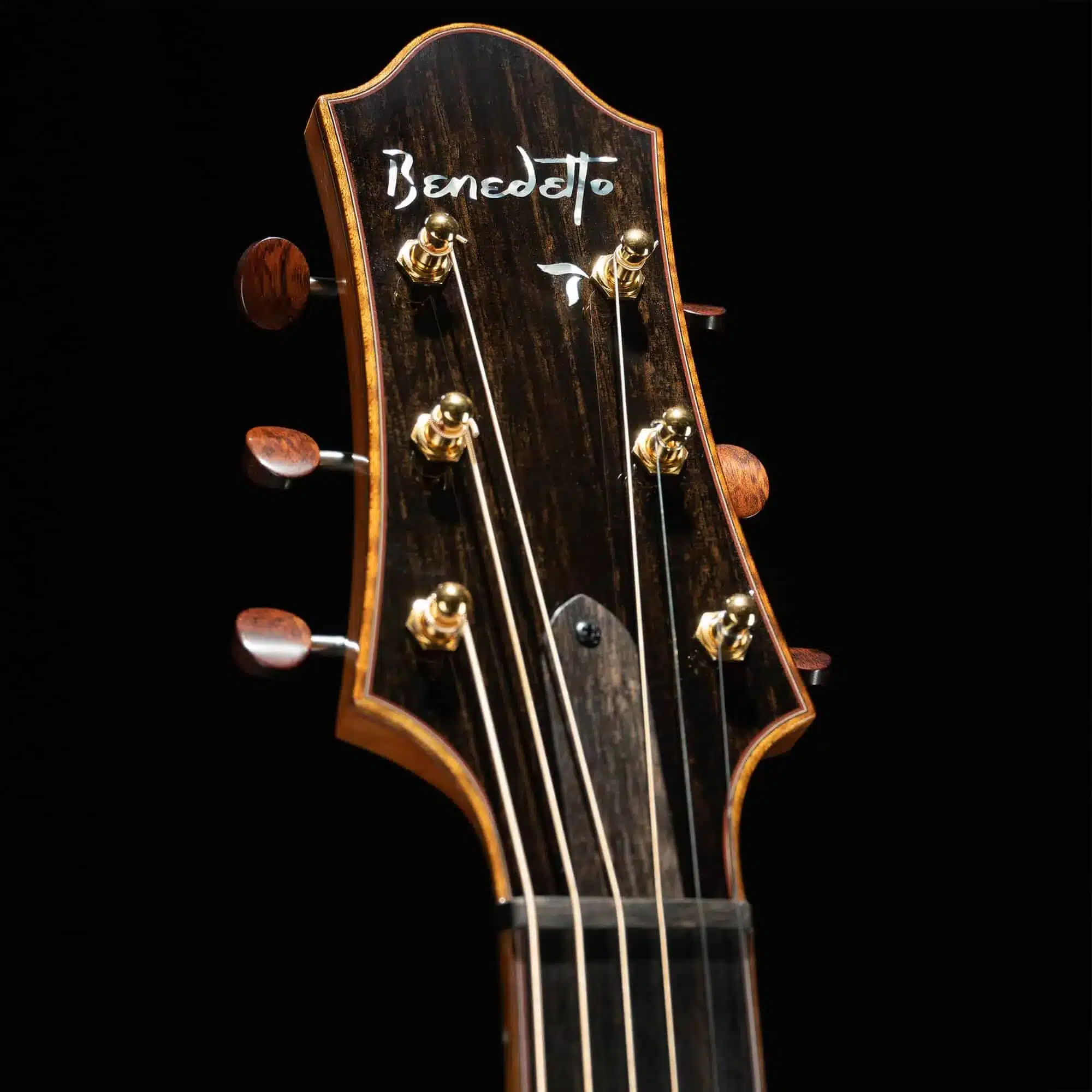 Benedetto archtop guitar headstock showcasing hand-crafted details, gold tuning pegs, and signature logo, emphasizing quality