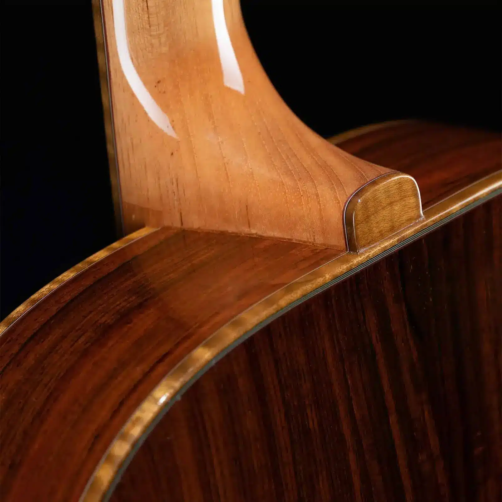 Close-up of a handcrafted wood neck joint and flamed maple binding on a Benedetto archtop guitar body.