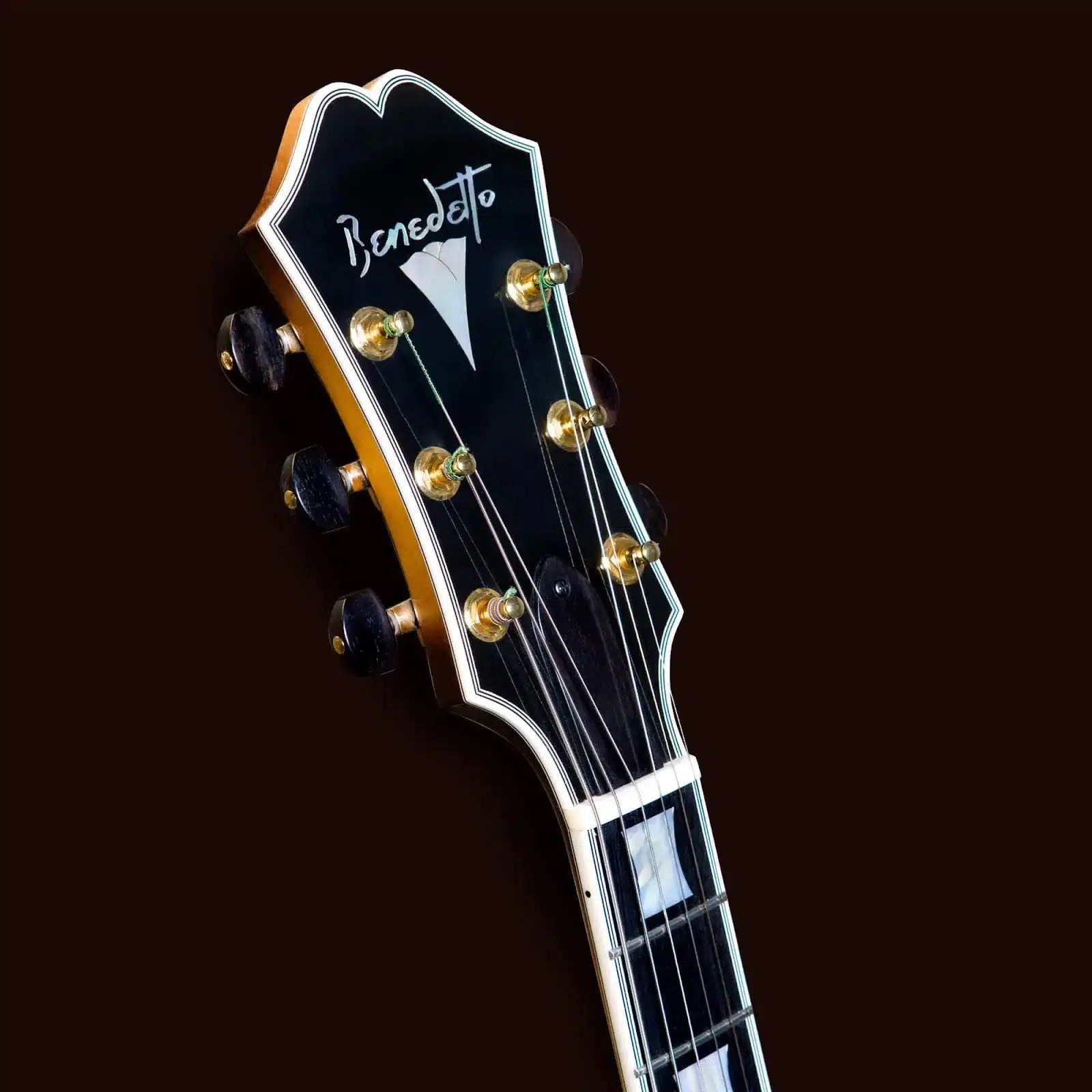 Benedetto guitar headstock with pearl inlay, gold tuning pegs, and ebony truss rod cover